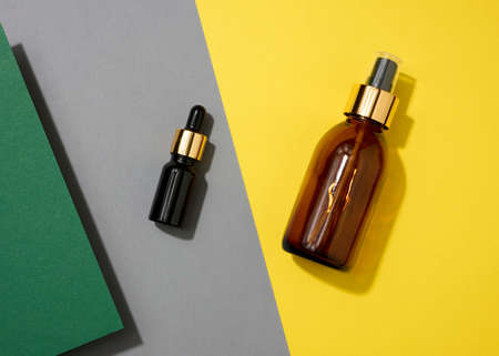 glass cosmetic brown bottles with a pipette on a yellow background. Cosmetics SPA branding mockup, top viewの写真素材