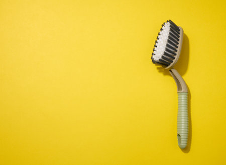 plastic brush with handle for cleaning the house on a yellow background, top view. Copy spaceの写真素材
