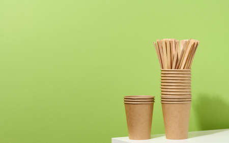 brown paper cardboard cups and wooden stirring sticks on a white table, green background. Eco-friendly tableware, zero wasteの写真素材