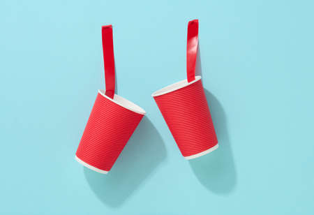 red cardboard cup glued with red sticky tape to the blue backgroundの写真素材