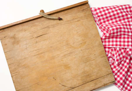 empty rectangular wooden kitchen cutting board and red towel in a white cage on a white table, top viewの写真素材