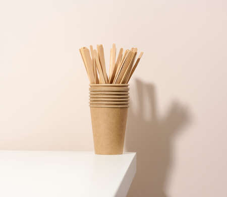 brown paper cardboard cups and wooden stirring sticks on a white table, beige background. Eco-friendly tableware, zero wasteの写真素材