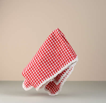 red and white checkered kitchen towel levitates on beige gray backgroundの写真素材
