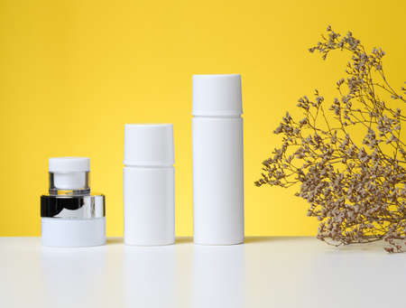 empty white plastic tubes and jars for cosmetics. Packaging for cream, gel, serum, advertising and...