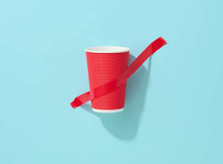 red cardboard cup glued with red sticky tape to the blue backgroundの写真素材