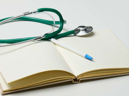 open blank notebook with pen and stethoscope, white tableの写真素材