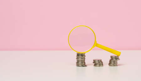 yellow magnifier and white coins on the table. Income growth concept, high percentage of investment....