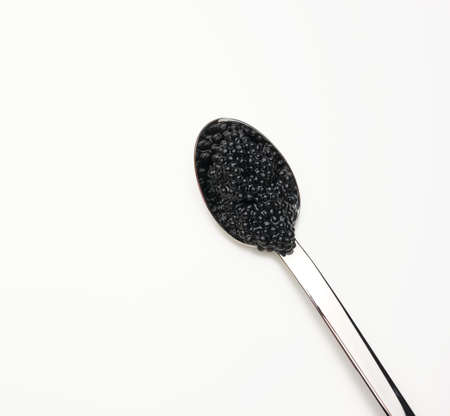 fresh grainy black paddlefish caviar in metal spoon on white background, top viewの写真素材