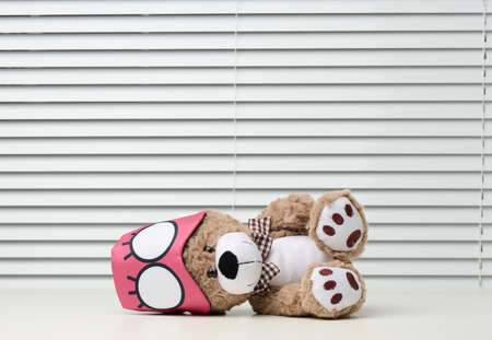 brown teddy bear sits with a bandage for sleeping on a white tableの写真素材