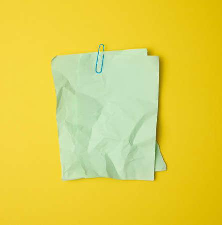 rectangular crumpled blank green sheet of paper on yellow backgroundの写真素材