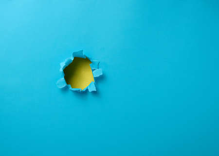 hole with torn edges in blue paper, full frame. Copy spaceの写真素材