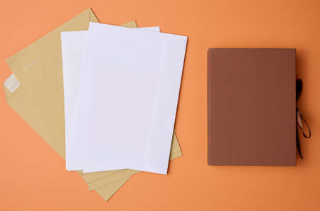 stack of white envelopes on orange background, top viewの写真素材