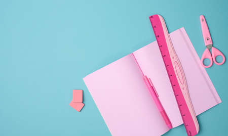 open notebook with blank pink sheets, scissors and ruler on blue background, top viewの写真素材