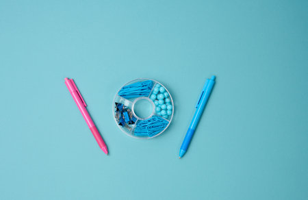 set of stationery objects: pen, paper clip, buttons and clip on a blue background. View from aboveの写真素材