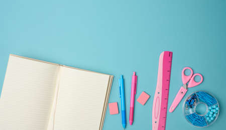 open notebook with blank pink sheets, scissors and ruler on blue background, top viewの写真素材