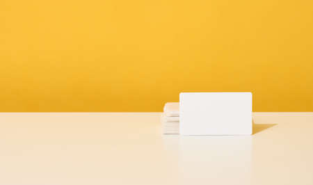 stack of white rectangular business cards on a yellow background, company branding, address.の写真素材