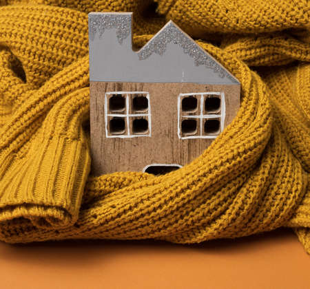 the wooden model of the house is wrapped in a warm knitted sweater. Loan concept for house insulation, alternative energyの写真素材