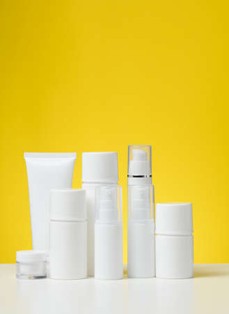 empty white plastic tubes and jars for cosmetics. Packaging for cream, gel, serum, advertising and...