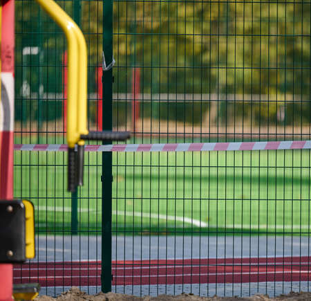 red and white prohibitory tape on the fence of the sports complex. Closed for visiting, quarantine