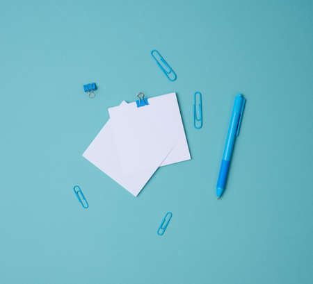 stack of white square sheets of paper for notes, stationery on blue background, top viewの写真素材