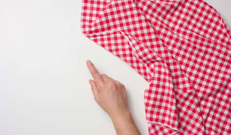 female hand with raised forefinger and red kitchen napkin on white table, top viewの写真素材