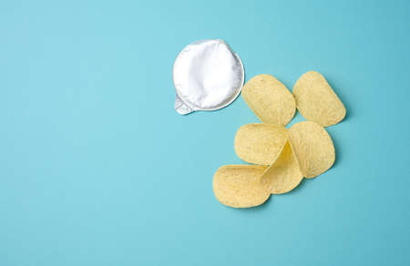round potato chips and foil lid on blue background, top view. Copy spaceの写真素材