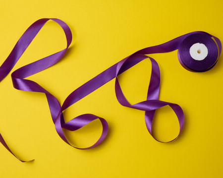 twisted purple textile ribbon for decoration on a yellow background, flat layの写真素材