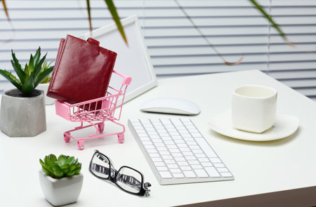 miniature shopping cart with leather wallet, keyboard on white table. Online shopping concept, start of salesの写真素材