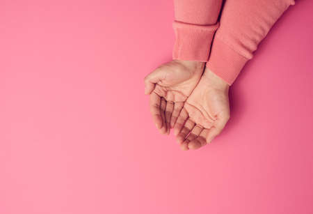 two female hands folded palm to palm on a pink background, top viewの写真素材
