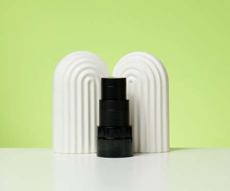 black glass jars for cosmetics on a white table. Packaging for cream, gel, serum, advertising and product promotion, mock up