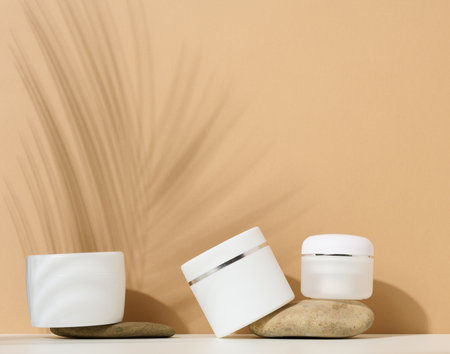white round plastic jar for cosmetic products on a brown background. Palm leaf shadow. Blank for branding products, mock upの写真素材