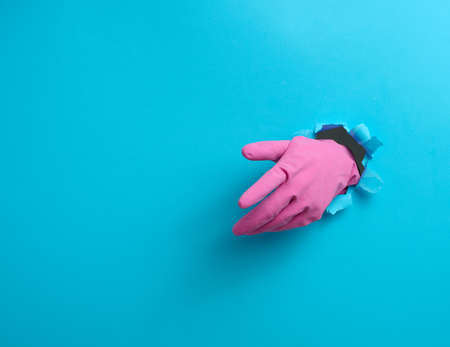 hand in a pink latex glove points a finger on a blue background. Place for inscription of discounts, offer or announcement.の写真素材