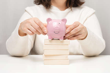 pink ceramic piggy bank and wooden blocks. Concept of increasing interest on a deposit in a bank, high return on investment, large margin on saleの写真素材