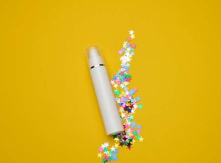 white plastic cosmetic bottle with dispenser and transparent cap on yellow background. Packaging for cream, fluid and gelの写真素材