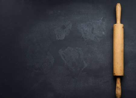 old wooden rolling pin for rolling dough on a black background, top view. Copy space