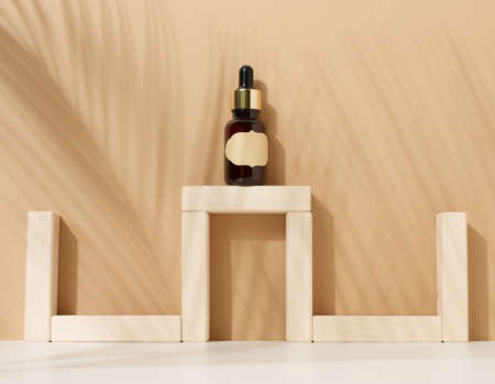 glass brown bottle with pipette and paper blank label on light brown background. Mockup skincare cosmetic productの写真素材