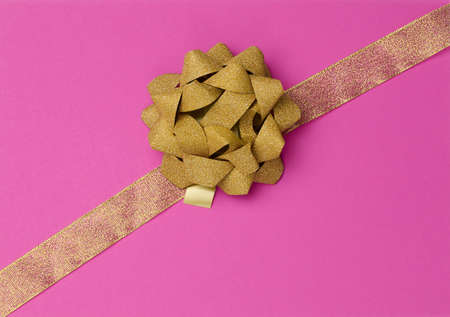 bow and golden silk ribbon on a pink background, design element for gift decor, lineの写真素材