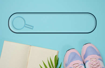 pair of pink sneakers and open notebook on a blue background, sports. Copy spaceの写真素材