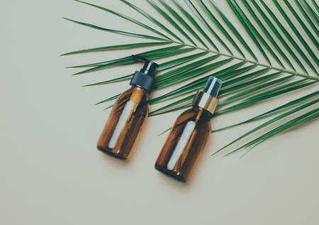 glass brown cosmetic bottles with spray and dispenser on a gray background, top view. Containers for...