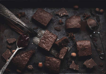 pieces of baked chocolate brownie pie in a metal baking sheet on a black table, top view
