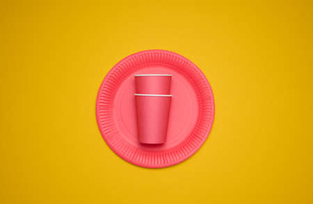 red paper cups and plates on a yellow background. Recyclable garbage, rejection of plastic, top viewの写真素材