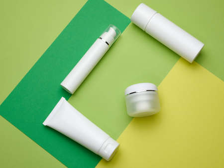 jar, bottle and empty white plastic tubes for cosmetics on a green background. Packaging for cream, gel, serum, advertising and product promotion, mock upの写真素材