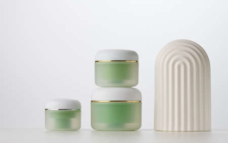 green jar for cosmetics on a white table. Packaging for cream, gel, serum, advertising and product...
