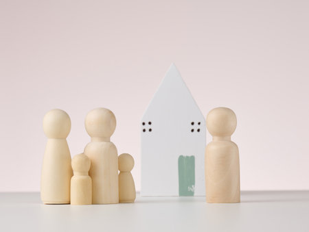 wooden figures of men and a miniature house on a beige background. The concept of buying or selling real estate, mortgage and property insuranceの写真素材