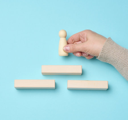wooden steps and a figurine of a little man in a woman's hand. Startup, starting a new successful...