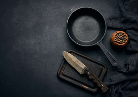 Empty round cast iron frying pan with wooden handle on black table, top viewの写真素材