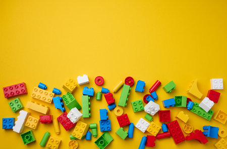 Scattered parts of a plastic children's designer, top view. Yellow background, copy spaceの写真素材