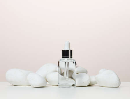 White glass transparent bottle with a pipette for cosmetics, oils, acids on a white tableの写真素材