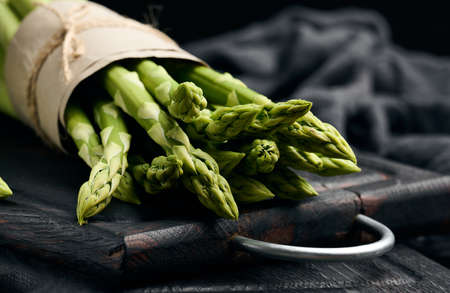 a bunch of fresh raw asparagus on a wooden black kitchen board, a healthy productの写真素材