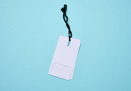 Blank rectangular paper white price tag with black rope on a blue background, flat layの写真素材